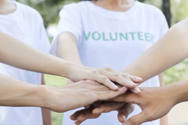 Close-up image of volunteers stacking hands to express support and unity before starting work